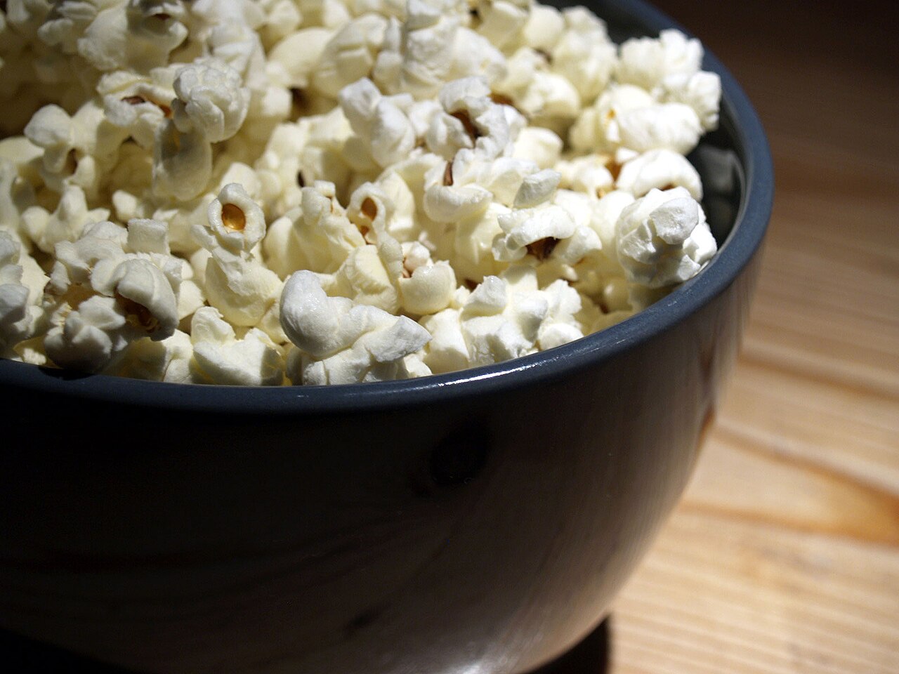 Freshly popped popcorn in a dark bowl