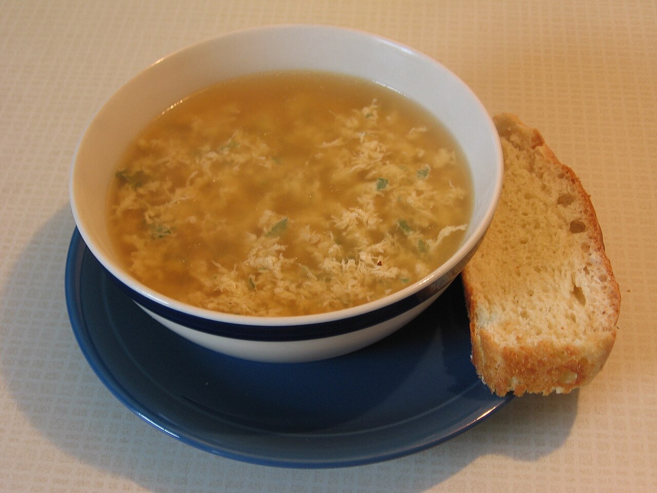 A bowl of stracciatella egg-drop soup with bread